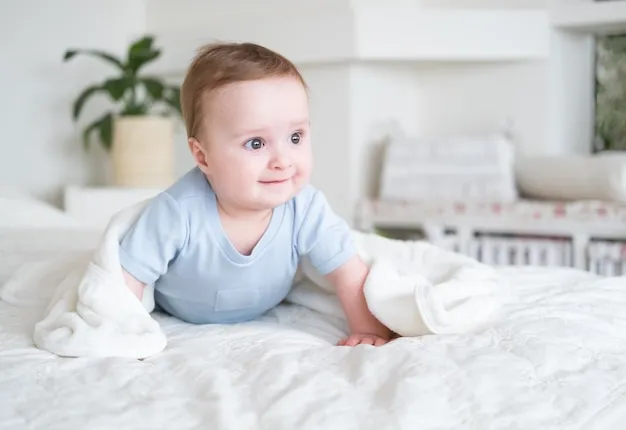 Bebé sonriente envuelto entre sábanas blancas