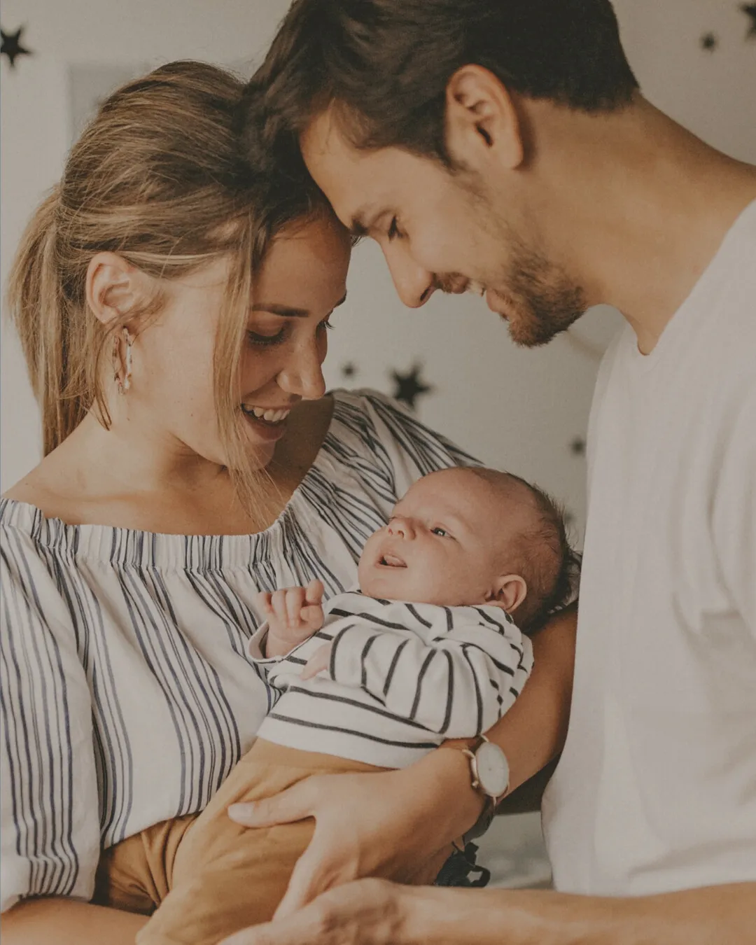 Padres sonriendo y mirando a su bebé recién nacido en brazos